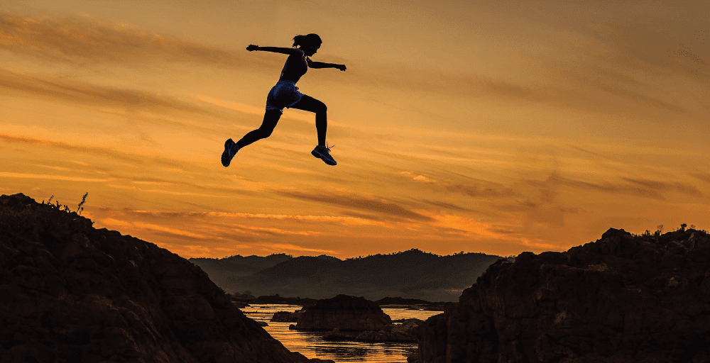 Person jumps over a mountain