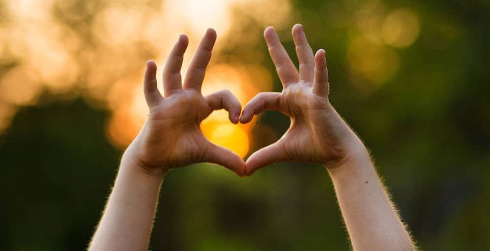 Heart shape hand of kid's body language for children's love, kindness, love concept. Heart Hand on nature sunset bokeh background