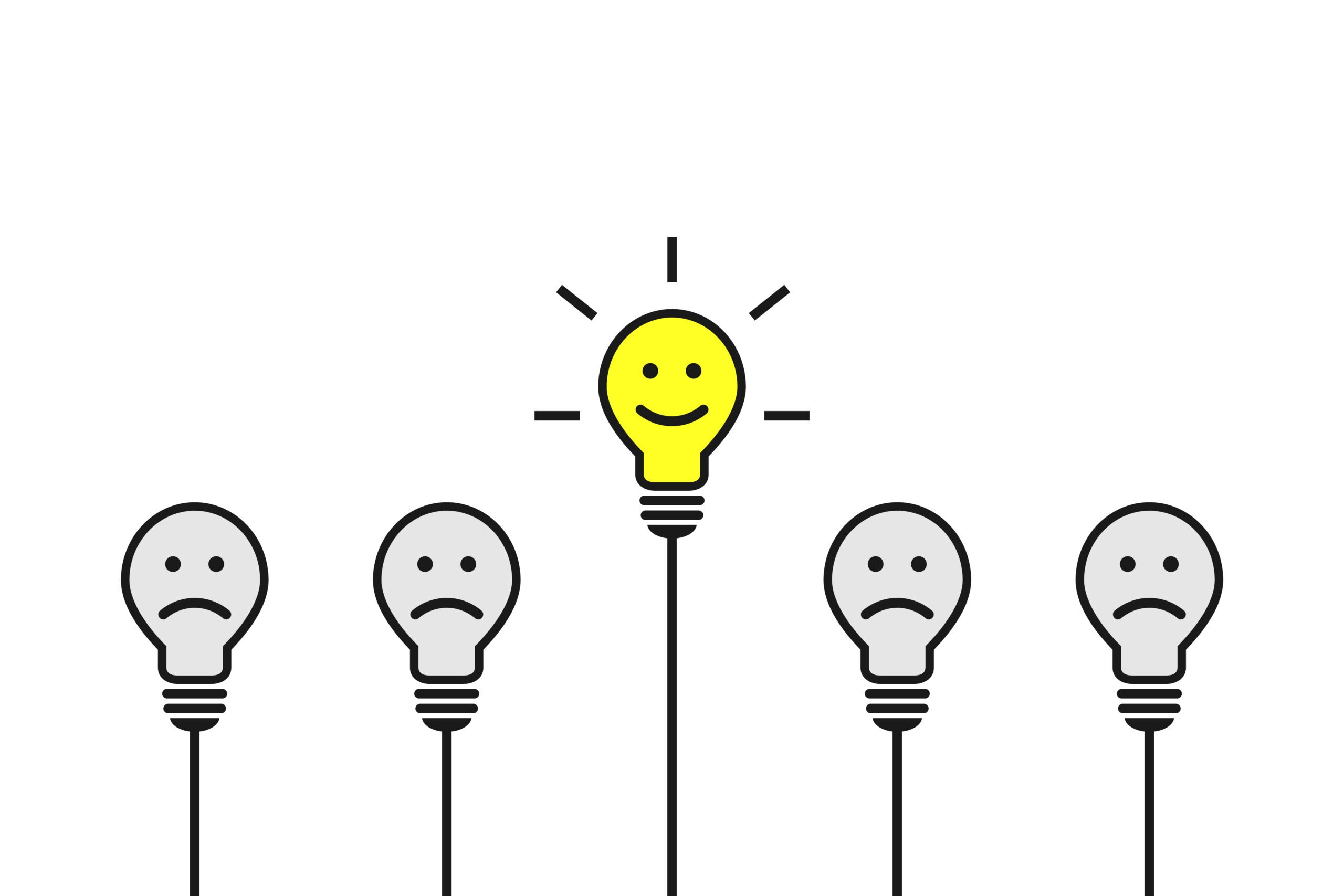 Smiling yellow cartoon light bulb being different and standing out from four other sad lightbulbs that are not shining bright.