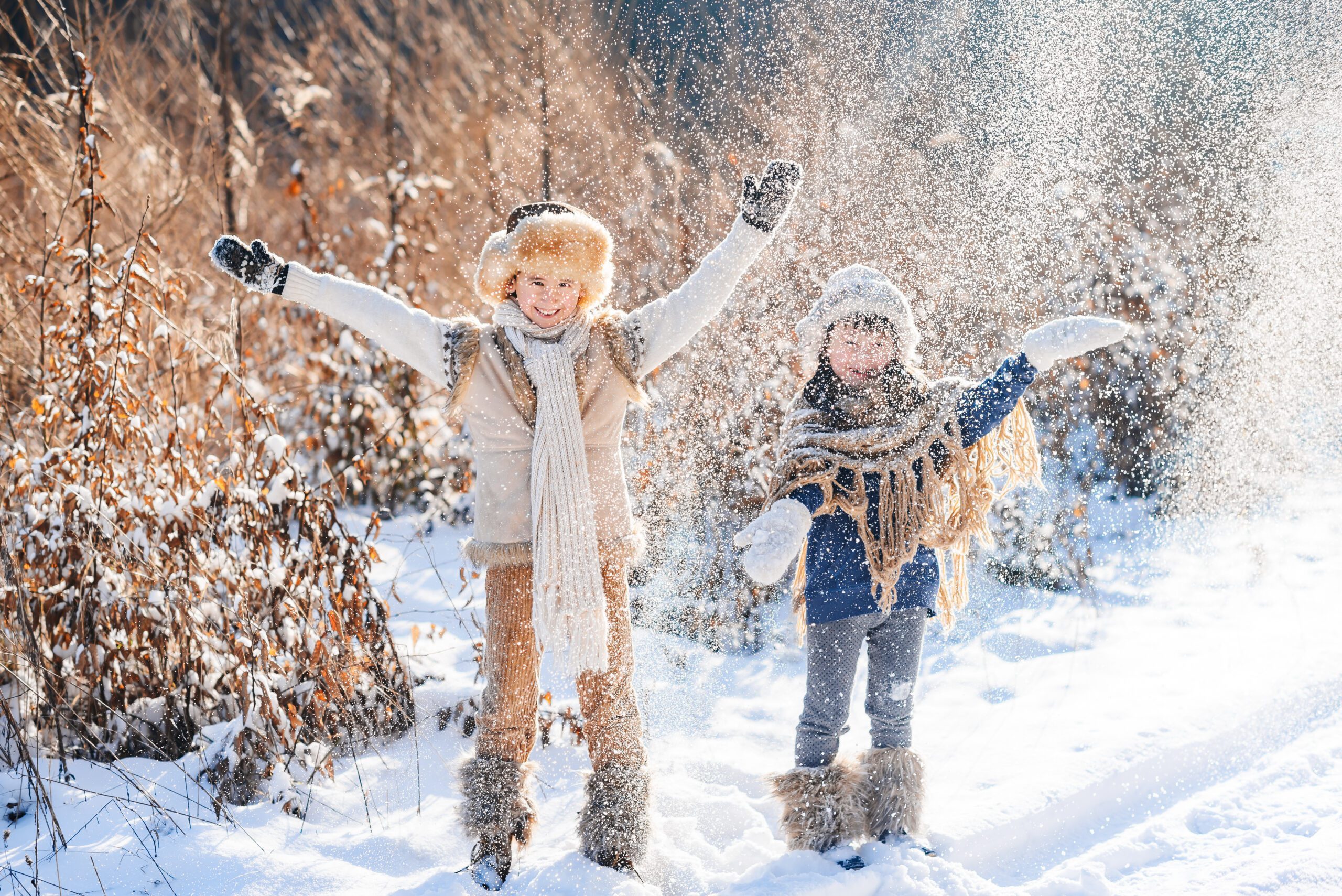 Happy children family playing with snow in winter time. Sunny cold winter day.